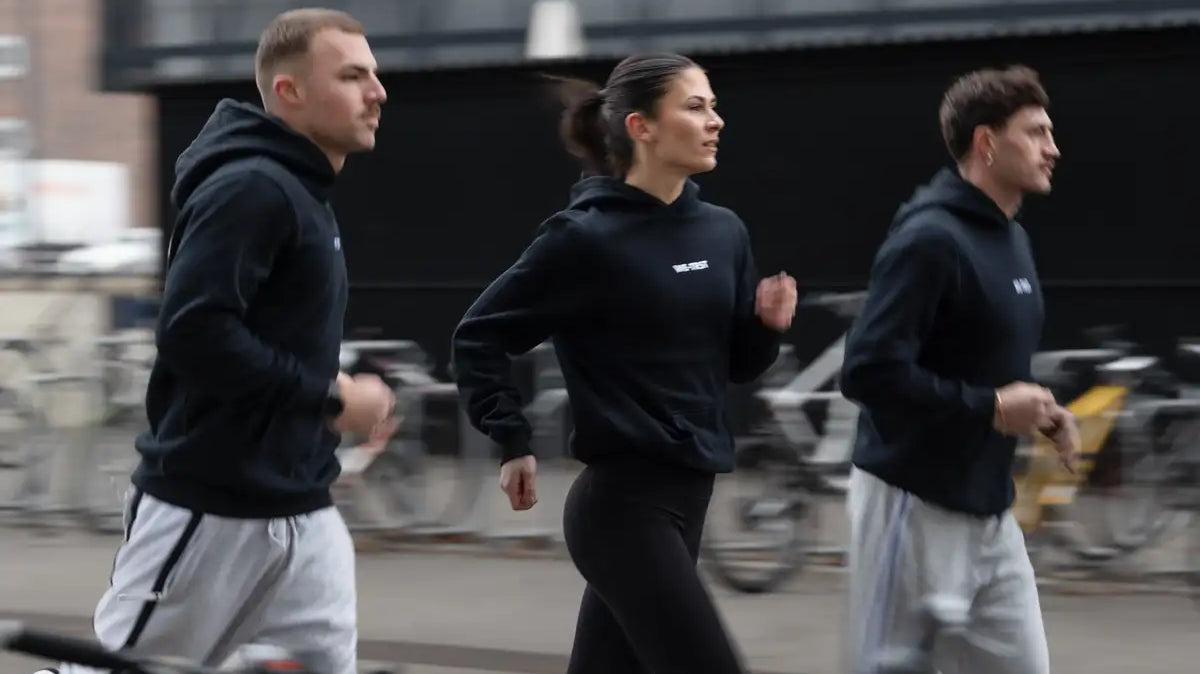 WE•TRST Run Club Zurich – drei Läufer in schwarzen Hoodies im urbanen Strassenlauf