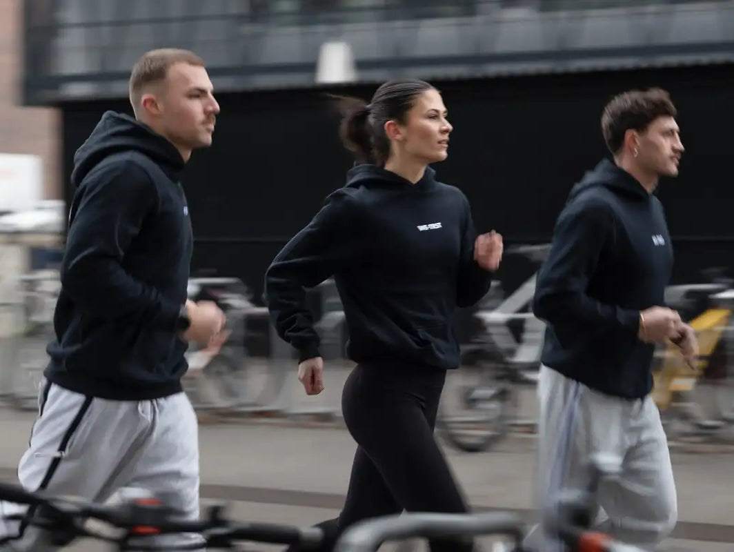 WE•TRST Run Club Zurich – drei Läufer in schwarzen Hoodies im urbanen Strassenlauf