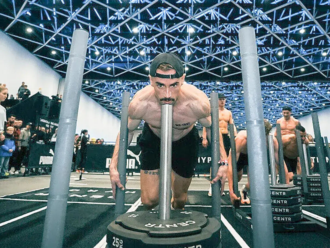 WE•TRST Athlet Michael Müller beim HYROX St. Gallen – Sled Push während des Indoor Fitness Race