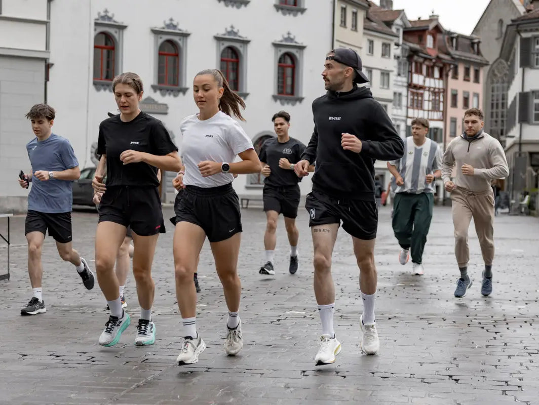 Läufer:innen des WE•TRST Run Clubs joggen durch die historische Altstadt von St. Gallen – Community Run bei bewölktem Wetter.