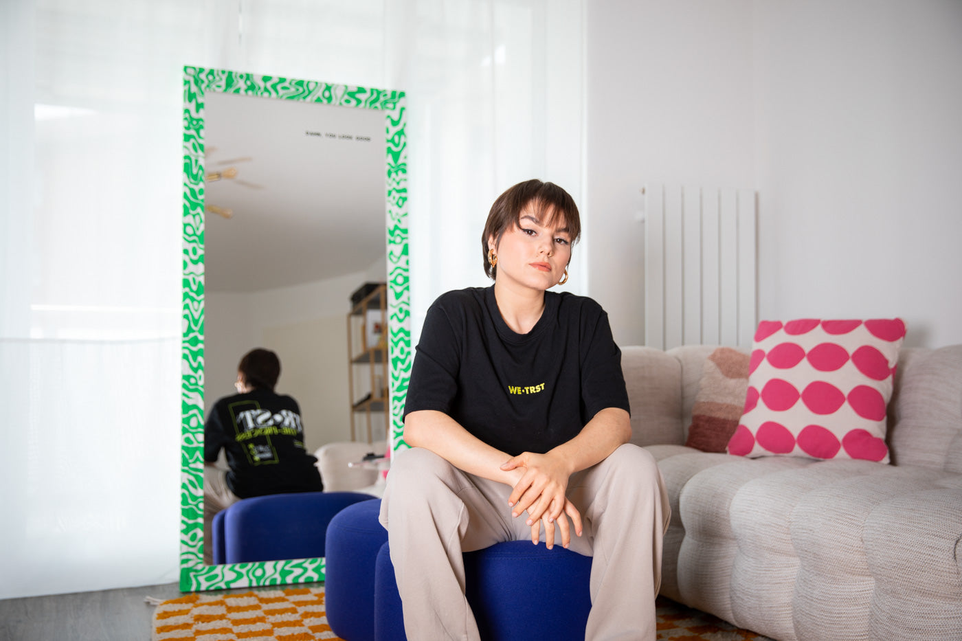Eine Make-up-Artistin, ist in ihrem Element, während sie ihre Kreativität entfaltet. Sie trägt ein stilvolles T-Shirt von WE•TRST, das ihre Unterstützung für Zusammenarbeit und Vertrauen ausdrückt.