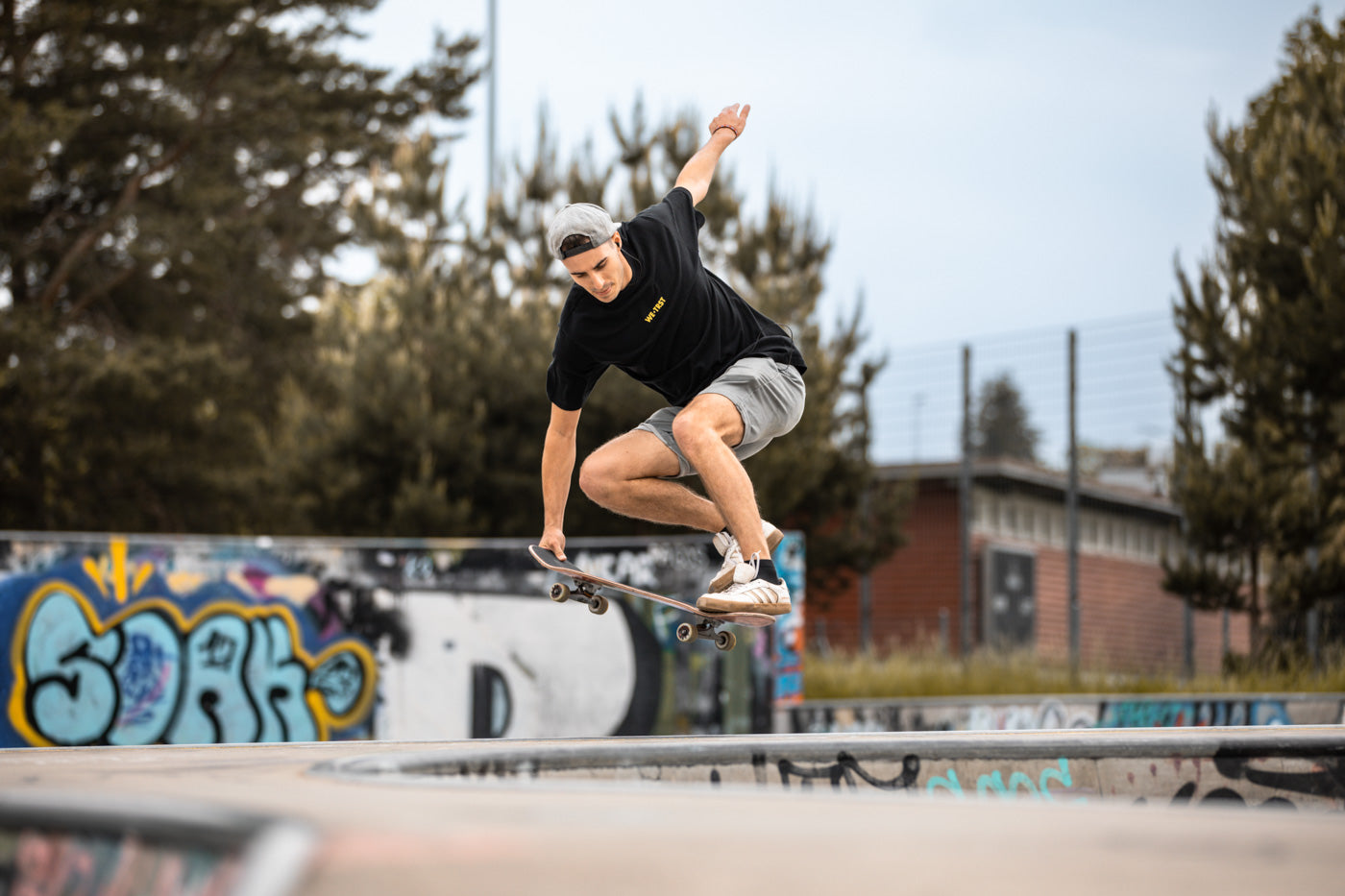 Ein Mann skatet gekonnt über eine Halfpipe. Er trägt ein stylisches T-Shirt von WE•TRST, das seinen individuellen Stil und seine Haltung repräsentiert.