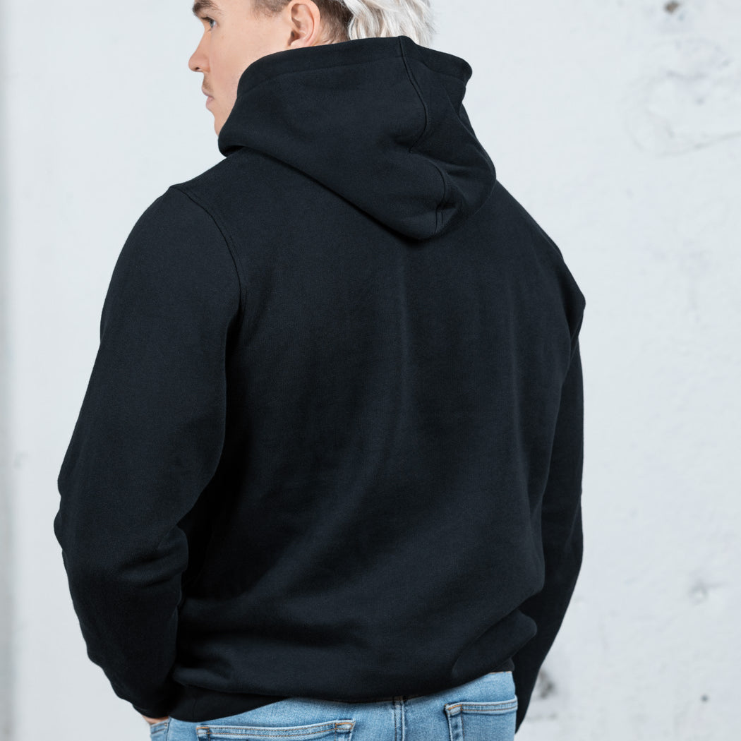 Rückenansicht eines männlichen Modells in einem schwarzen WE•TRST-Kapuzenpullover, wobei die übergroße Passform und das strukturierte Kapuzendesign hervorgehoben werden.
