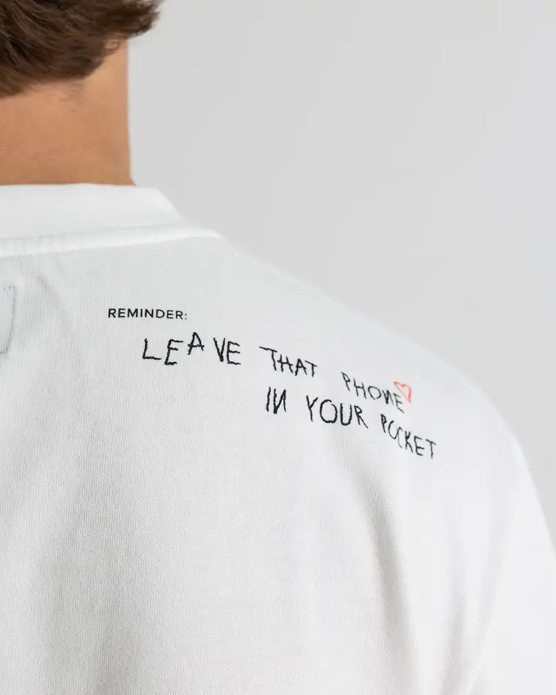 Schulter-Detail des Dangel Twins-Shirts mit handgeschriebenem Reminder: Leave that phone in your pocket – WE•TRST Streetwear-Statement.