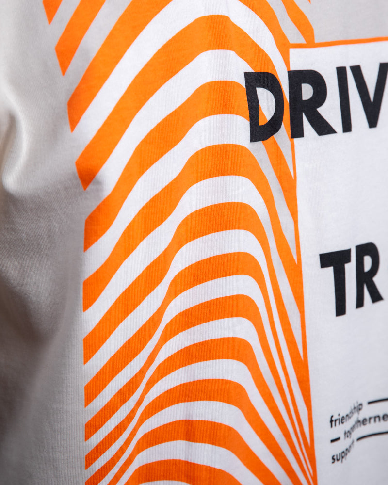 Nahaufnahme des Rückendrucks auf dem WE•TRST-T-Shirt „Driven by Trust“ mit leuchtend orangefarbenen Wellenmustern und Typografie.