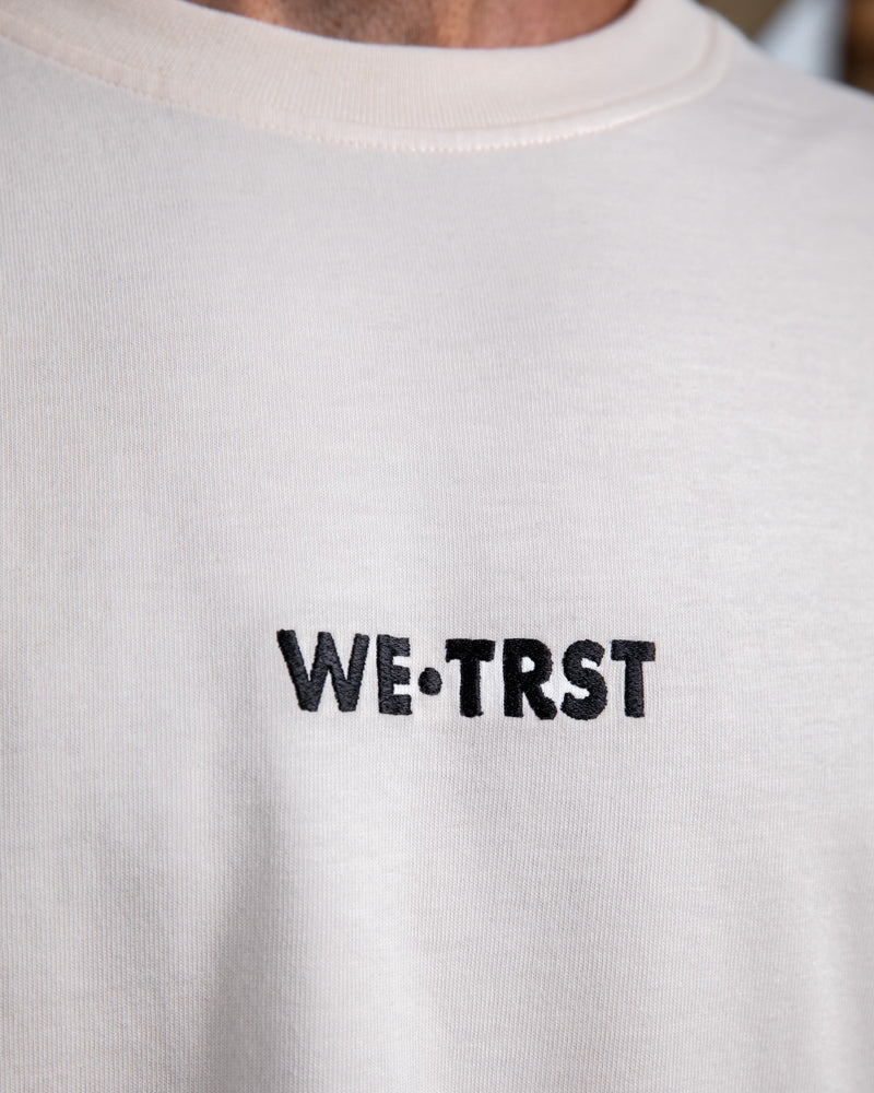 Nahaufnahme des gestickten WE•TRST-Logos auf der Vorderseite des übergroßen T-Shirts „Driven by Trust“, das die hochwertige Verarbeitung betont.