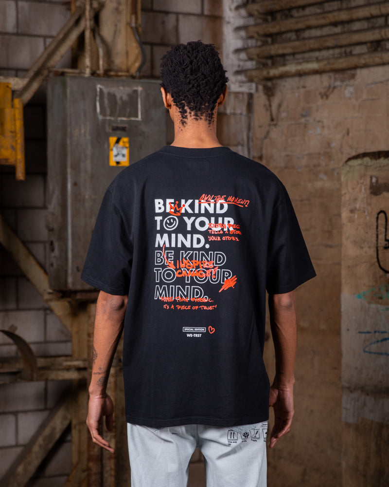 Rückenansicht eines männlichen Models, das das WE•TRST Special Edition T-Shirt trägt, auf dem die Typografie „Be Kind to Your Mind“ zu sehen ist.