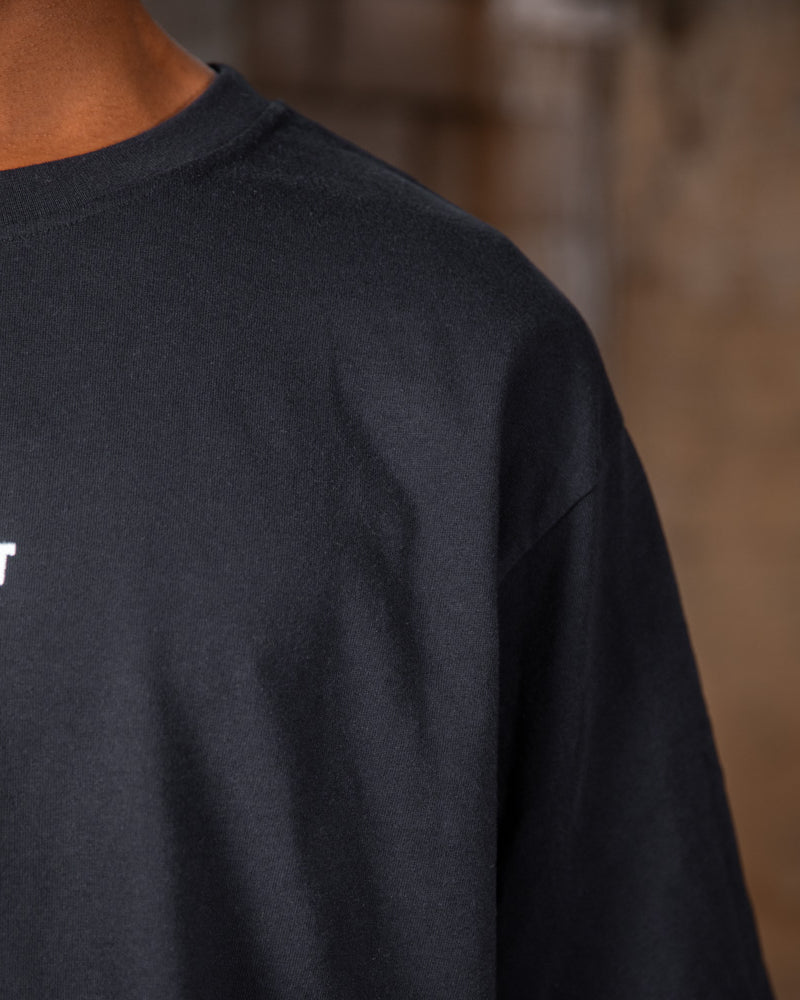 Nahaufnahme des WE•TRST-Logos auf dem schwarzen Special-Edition-T-Shirt, das das minimalistische Design der Vorderseite betont.