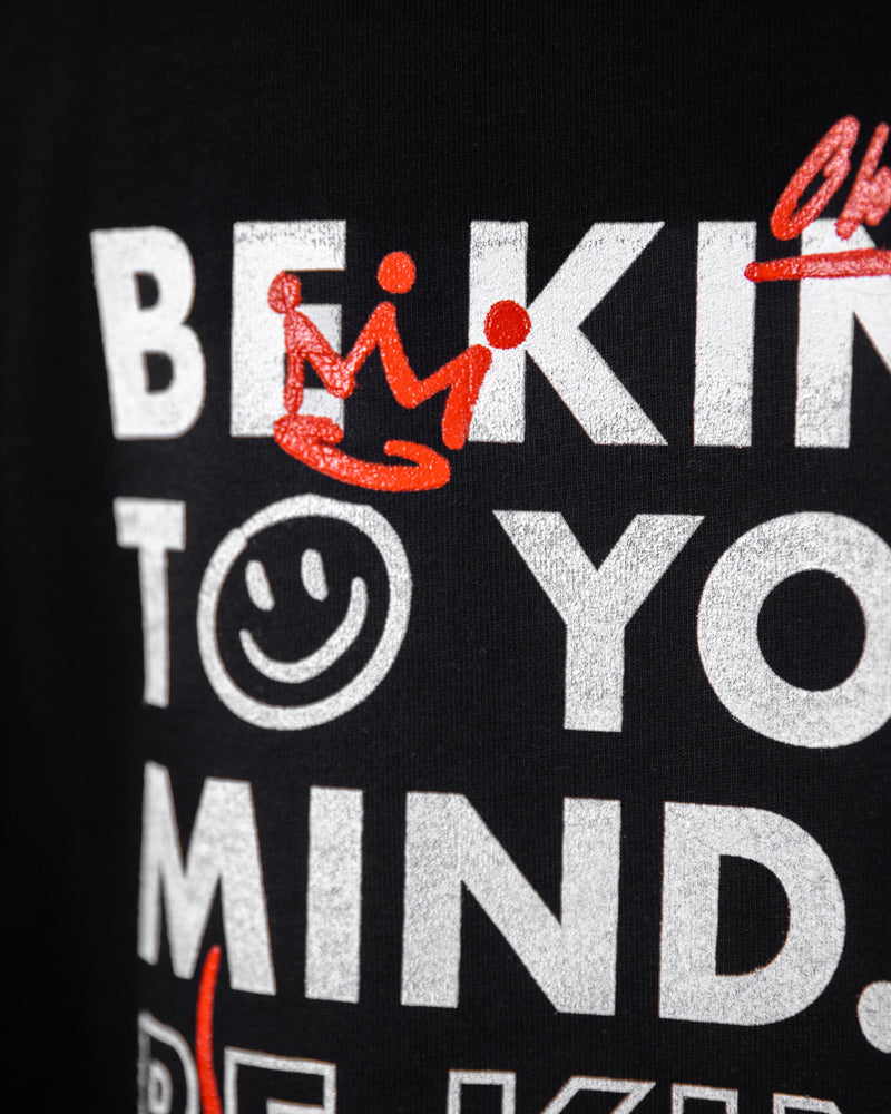Detaillierte Nahaufnahme des grafischen Aufdrucks „Be Kind to Your Mind“ auf dem WE•TRST Special Edition T-Shirt mit weißen und roten Typografie-Elementen.