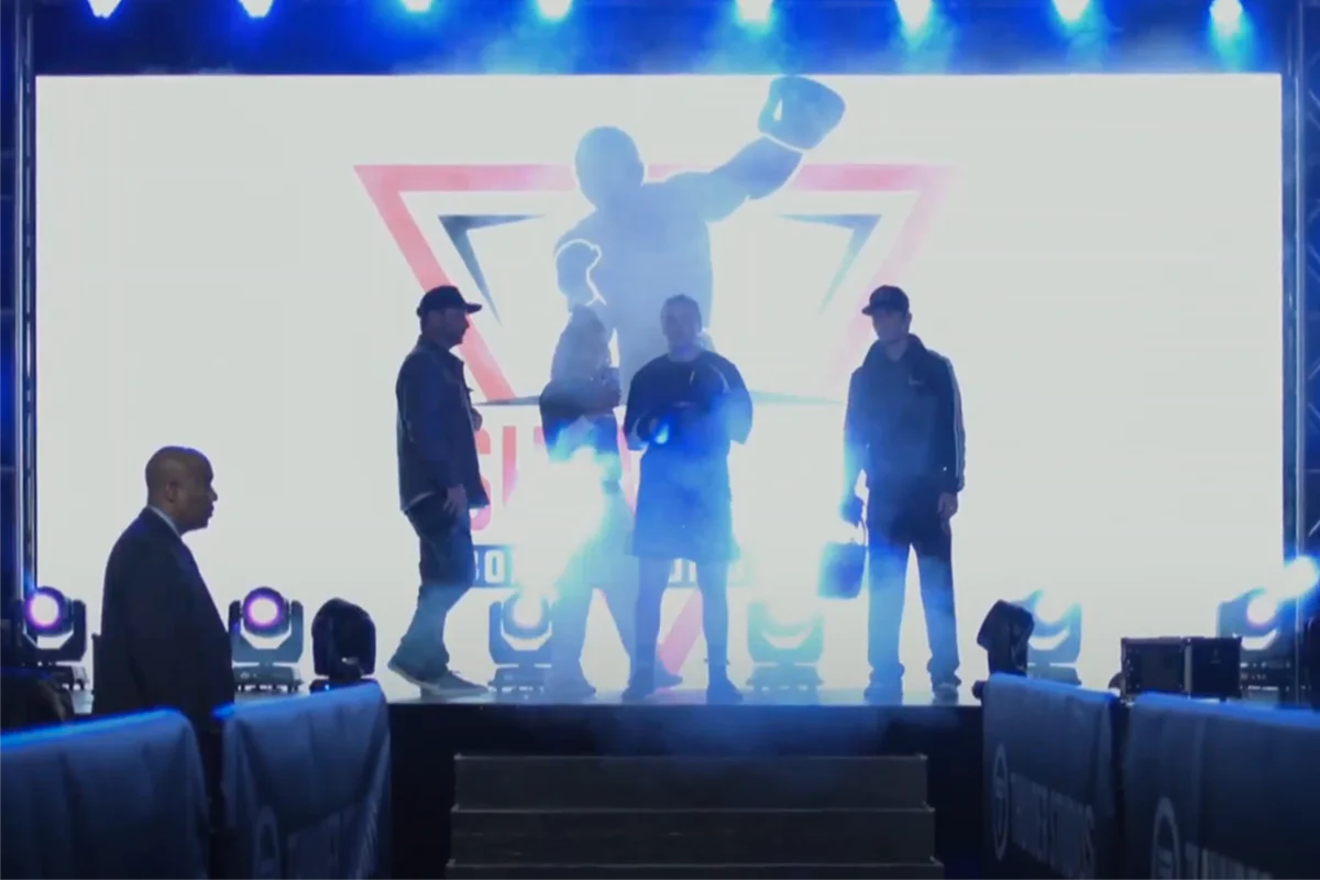 Julia Igel and team entering the arena with dramatic backlighting and fog, in front of a large boxing-themed LED screen during a professional event