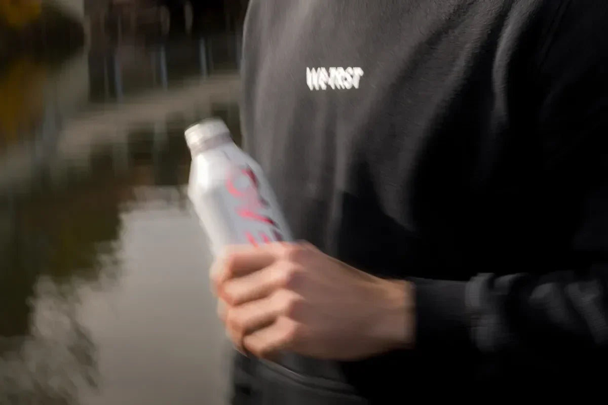 WE•TRST Run Club Teilnehmer in schwarzem Hoodie mit PEAQ Getränk in St. Gallen