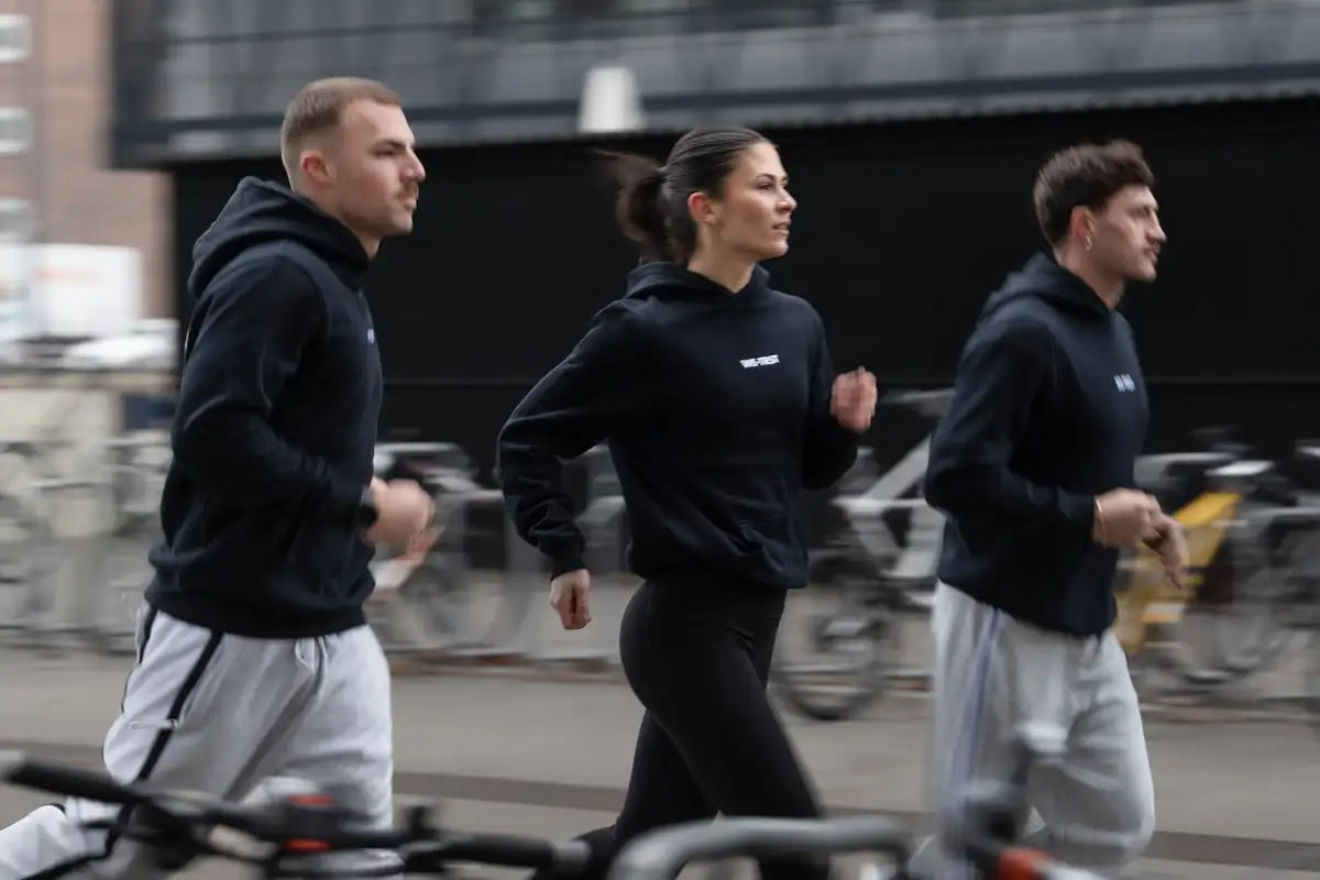 WE•TRST Run Club Zurich – drei Läufer in schwarzen Hoodies im urbanen Strassenlauf
