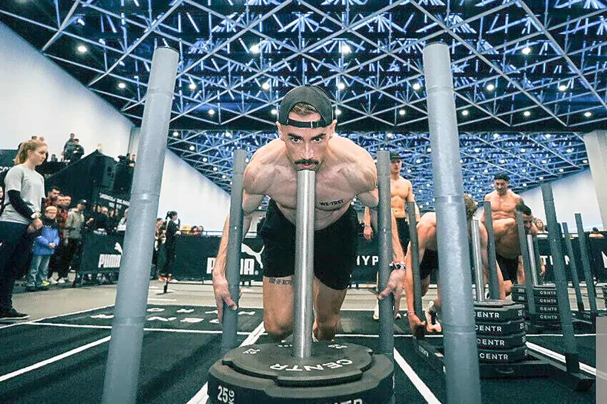 WE•TRST Athlet Michael Müller beim HYROX St. Gallen – Sled Push während des Indoor Fitness Race