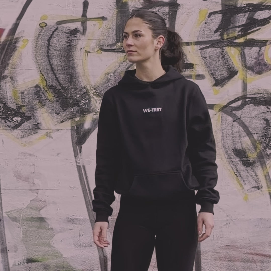 WE•TRST Run Club Community – Eine Athletin in schwarzer Performance Streetwear von WE•TRST im urbanen Raum