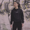 WE•TRST Run Club Community – Eine Athletin in schwarzer Performance Streetwear von WE•TRST im urbanen Raum