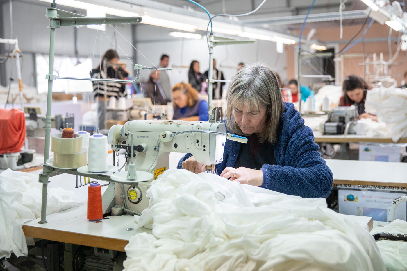 Eine Näherin die konzentriert an ihrer Nähmaschine arbeitet.