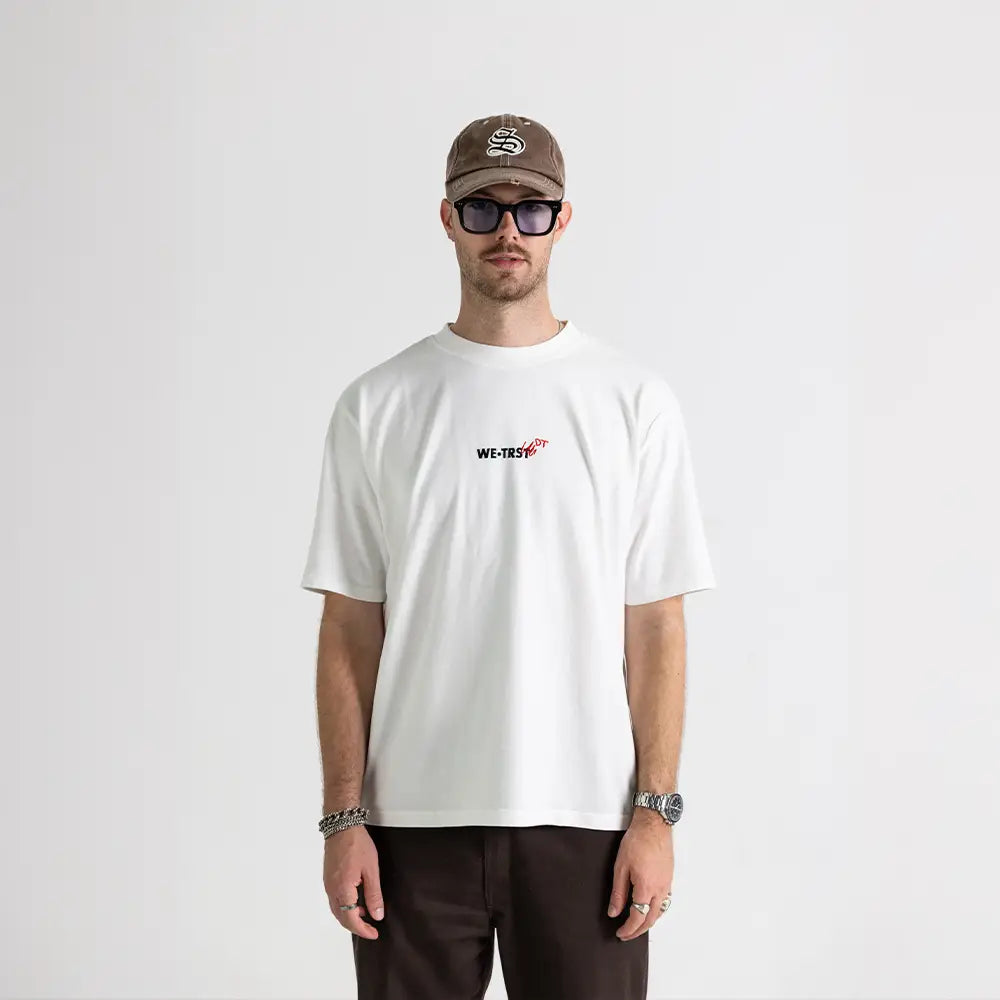 Chris Dangel von den Dangel Twins mit brauner Cap und Sonnenbrille trägt das weisse WE•TRST Dangel Twins-Shirt in Studio-Setting – Frontansicht.