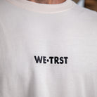 Nahaufnahme des gestickten WE•TRST-Logos auf der Vorderseite des übergroßen T-Shirts „Driven by Trust“, das die hochwertige Verarbeitung betont.