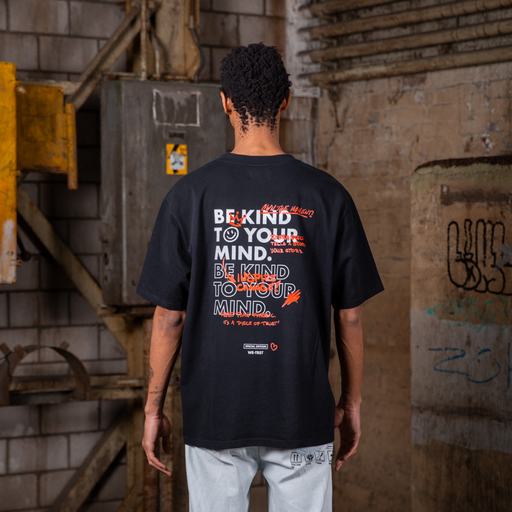 Rückenansicht eines männlichen Models, das das WE•TRST Special Edition T-Shirt trägt, auf dem die Typografie „Be Kind to Your Mind“ zu sehen ist.