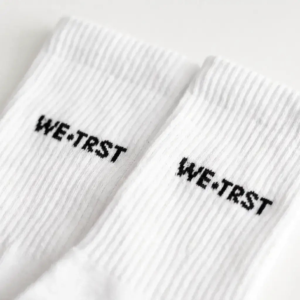 WE•TRST STEP•ONE Socks – Detailansicht Logo-Stickerei auf weissem Ripp