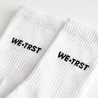 WE•TRST STEP•ONE Socks – Detailansicht Logo-Stickerei auf weissem Ripp